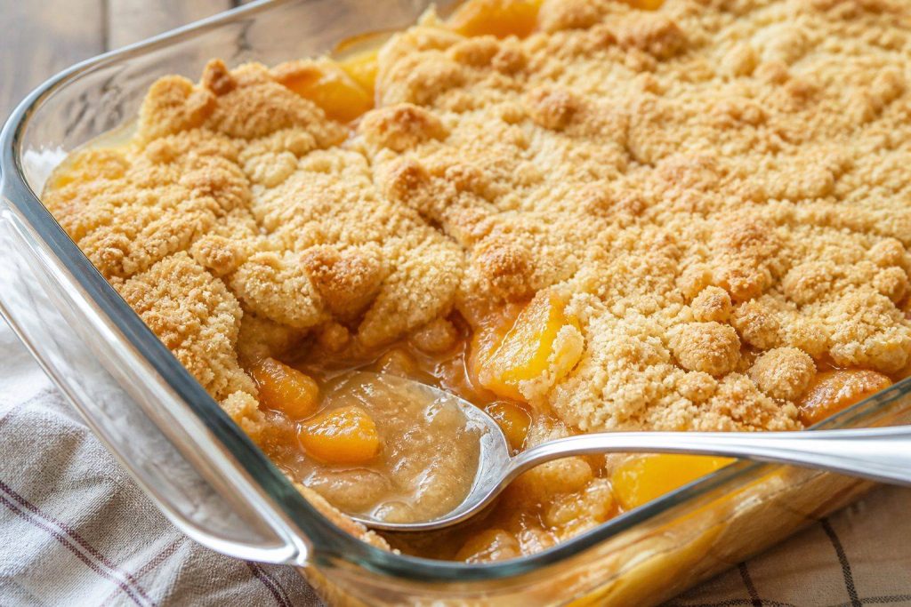 Peach dump cake in a glass baking dish with golden cake mix topping and bubbling peaches