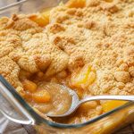 Peach dump cake in a glass baking dish with golden cake mix topping and bubbling peaches