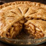 Double-crust apple pie with a slice removed showing cinnamon apples